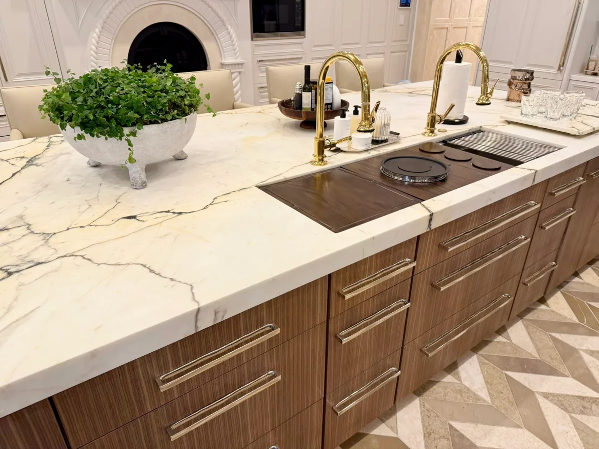 Walnut kitchen island with marble waterfall countertop and brass fixtures
